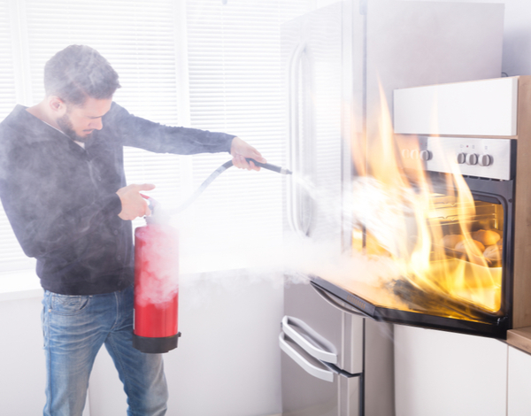 Man using a Fire extinguisher to stop the fire inside the oven