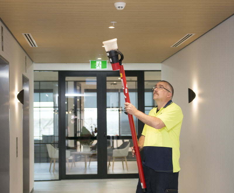 Fire safety expert cleaning the fire alarm