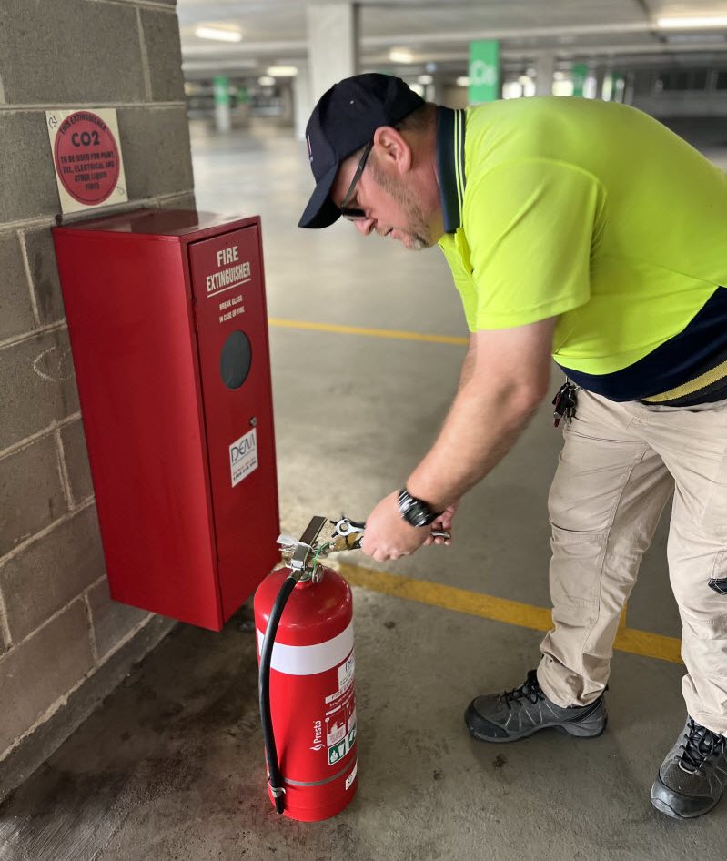 Man installing a fire extinguisher in a parking space