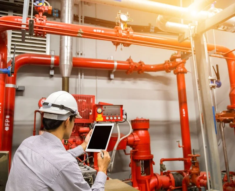 Engineer with tablet check red generator pump for water sprinkler piping and fire alarm control system